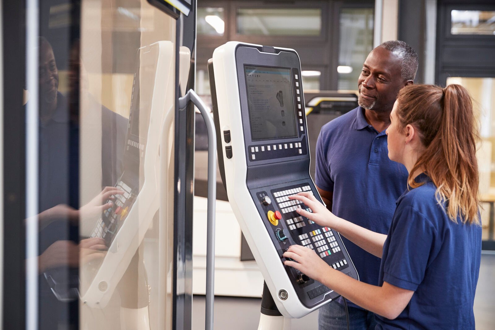 Operators at a CNC machining center control panel