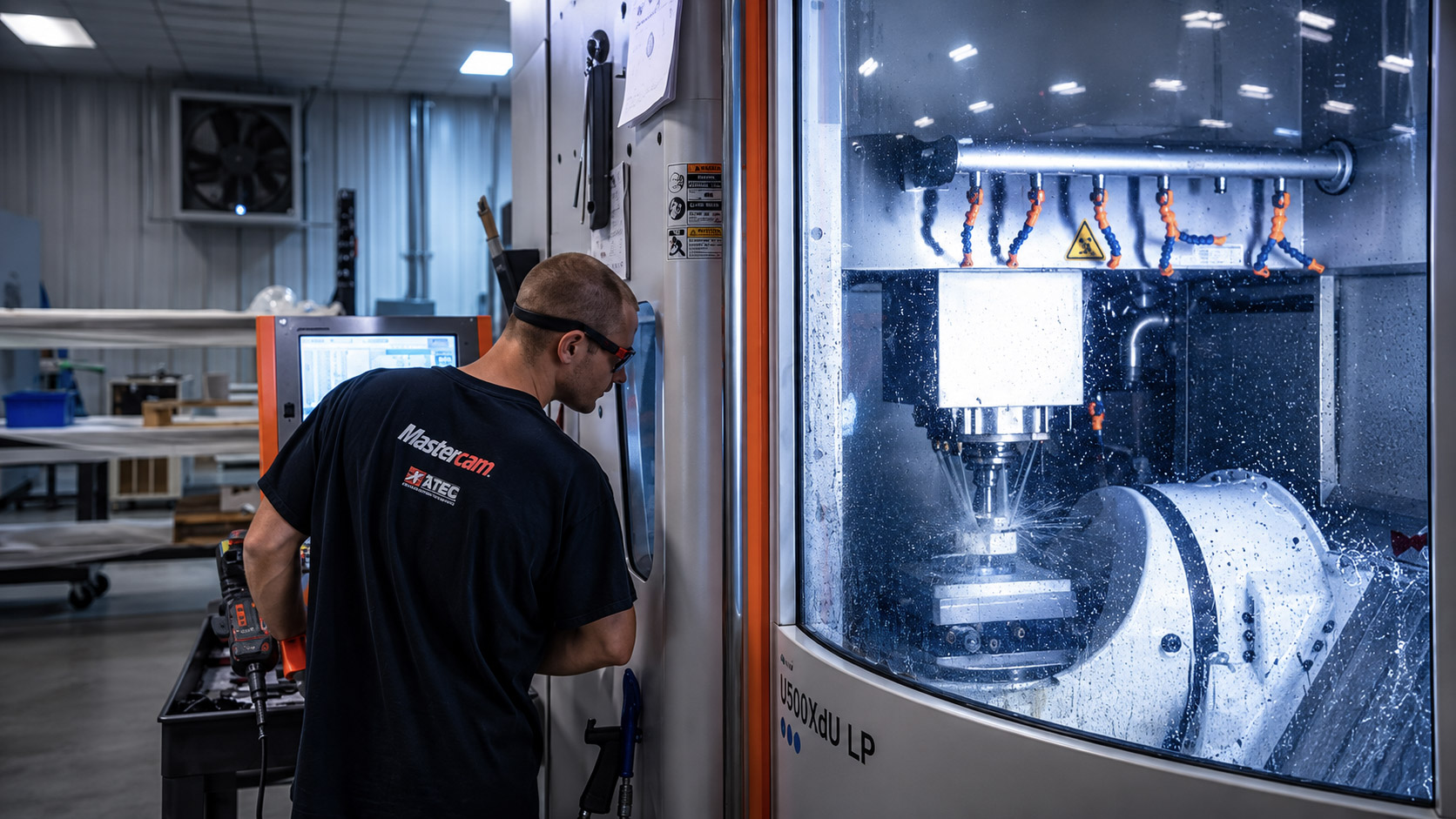 Machinist at the control of a 5-axis machining center mid-cut
