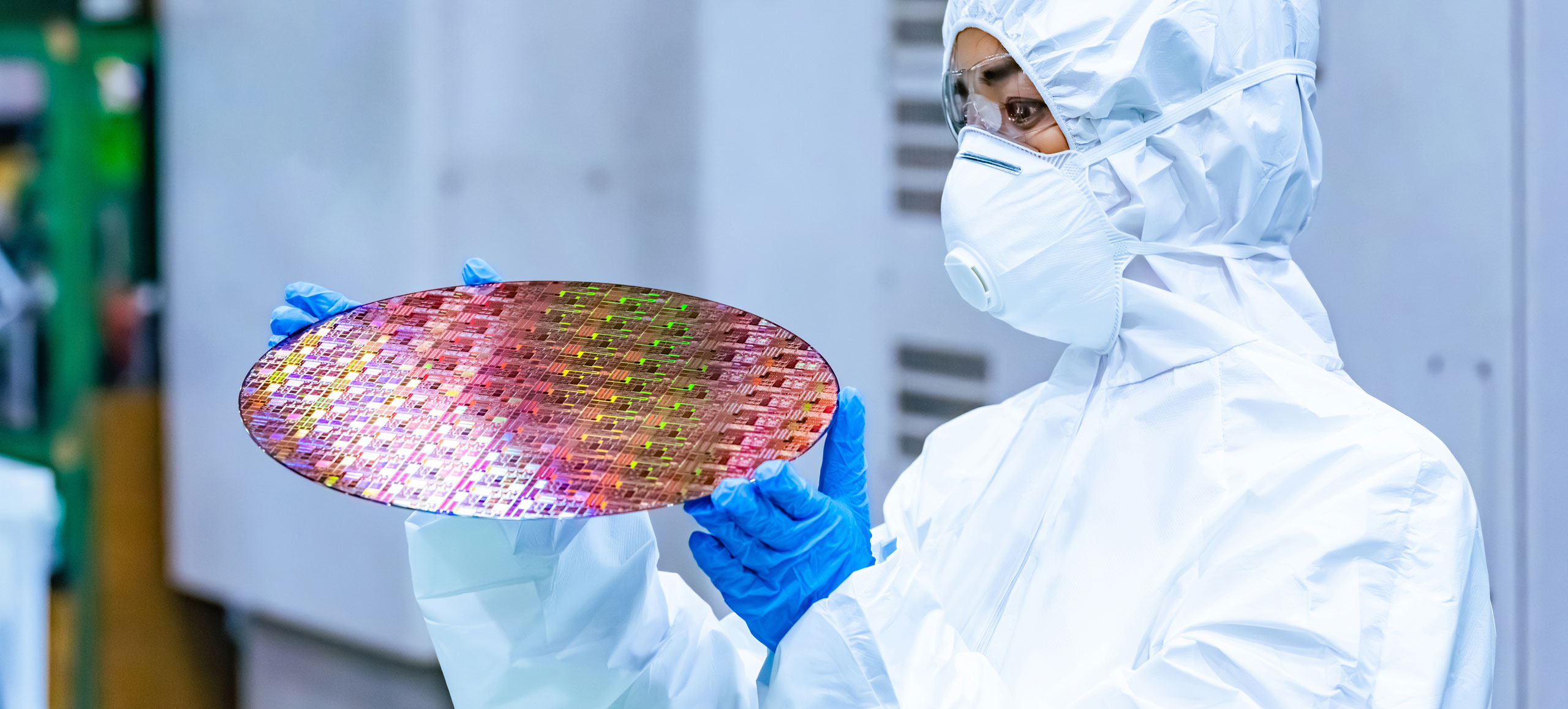 Cleanroom technician holding a semiconductor wafer